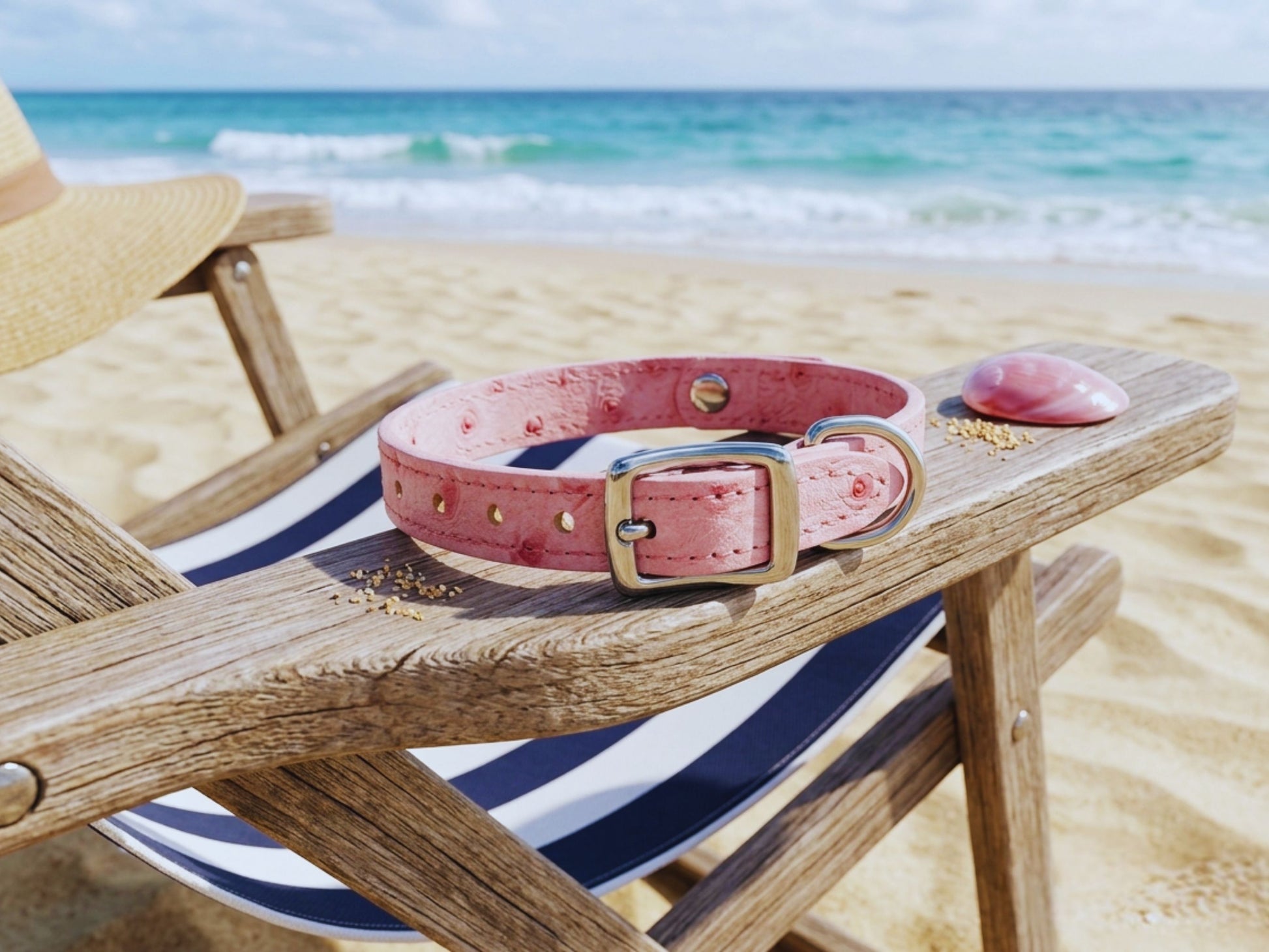 Close-up of buckle detail on pink ostrich leather dog collar draped over beach chair