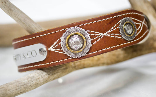 Brown leather dog collar with antique silver floral conchos and engraved silver nameplate — front view on white background