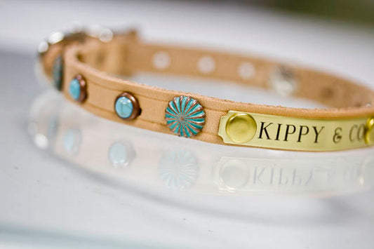 Close-up of tan leather dog collar with patina copper sunburst concho and turquoise cabochon stones
